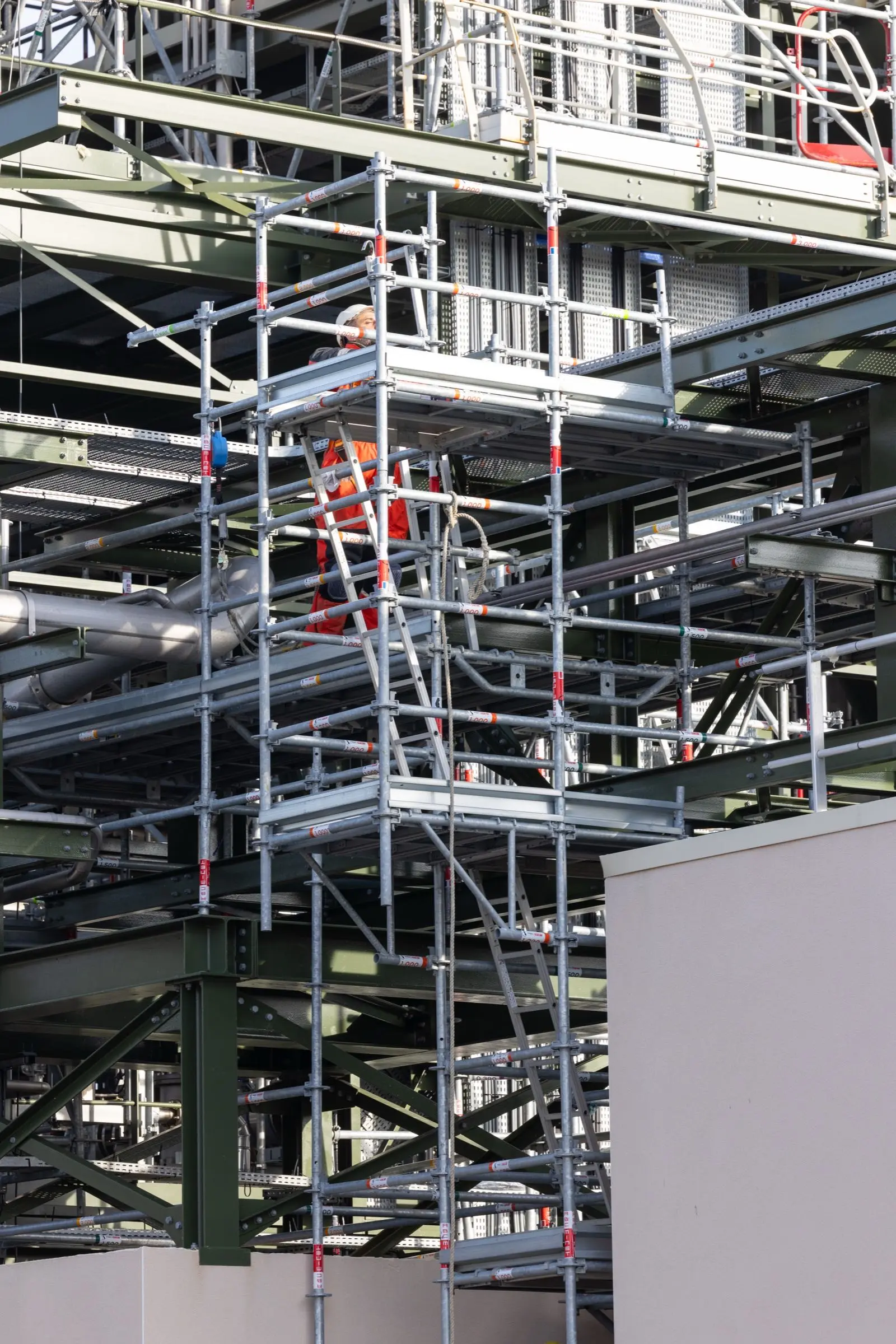Technicien en ascension sur un échafaudage en milieu industriel