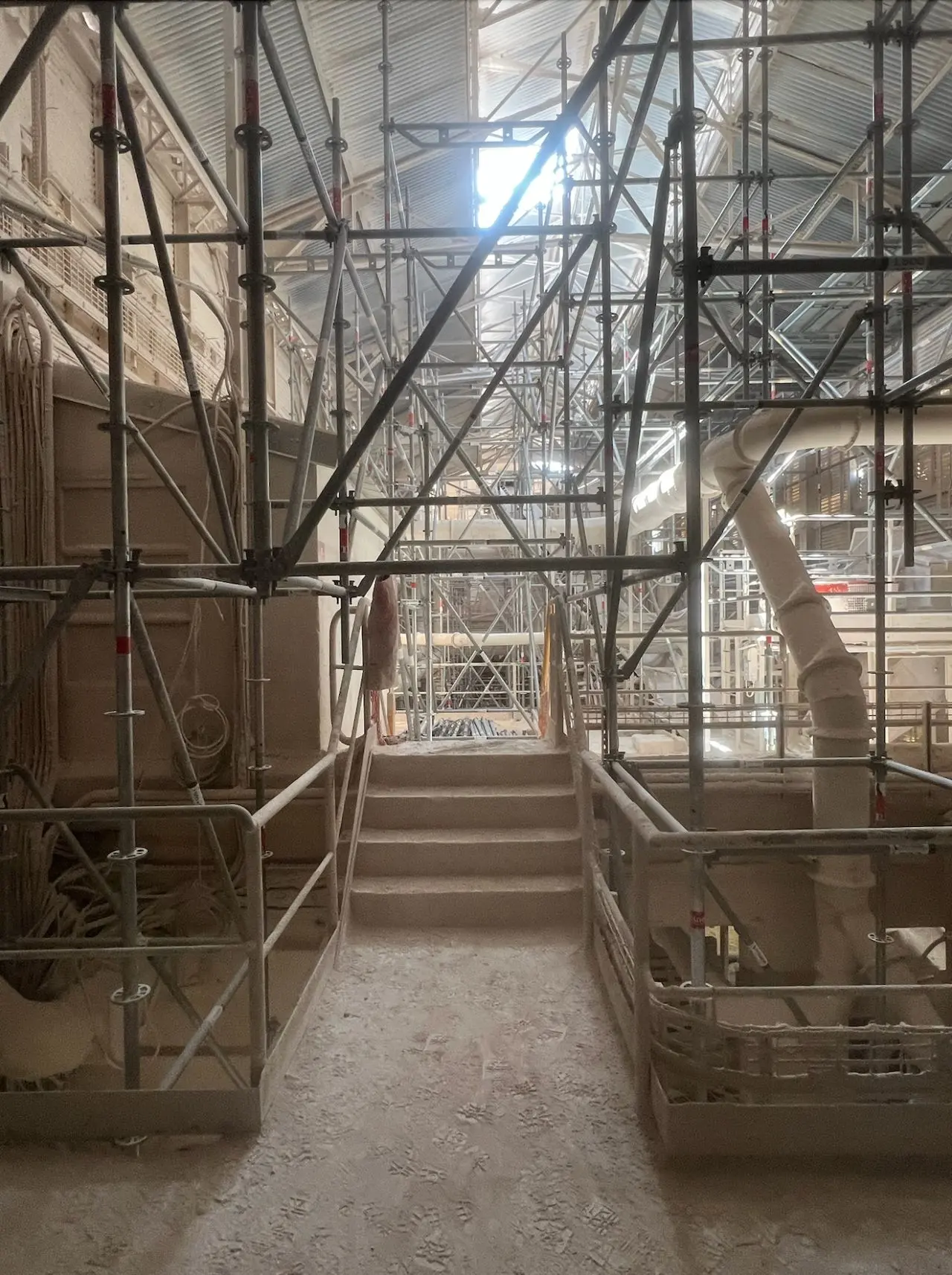 Structure d'échafaudage intérieur autoportante de gros tonnage, montée au-dessus des lignes de production actives pour la réfection de toiture industrielle.