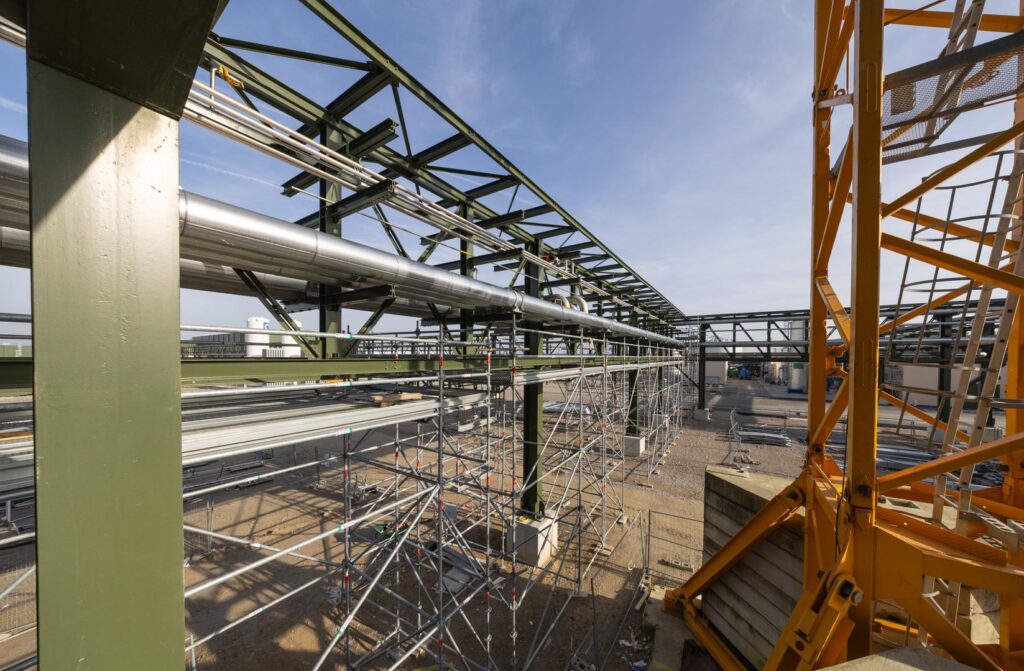 Vue d'ensemble d'un échafaudage industriel déployé sous une structure métallique et des réseaux de fluides pour des travaux de maintenance