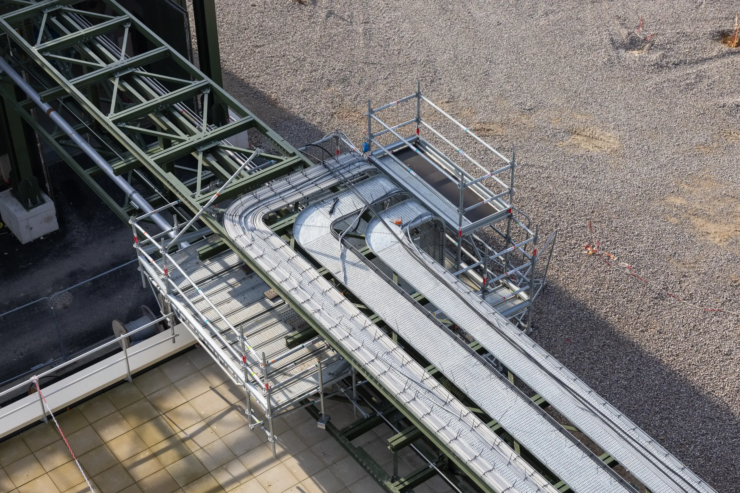 Vue de dessus d'une plateforme d'échafaudage technique installée pour la maintenance de chemins de câbles électriques sur un site industriel.