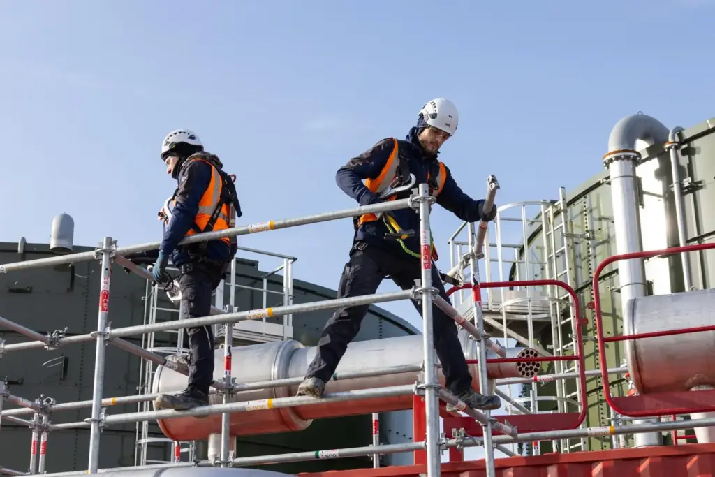 Travail en hauteur sécurisé sur chantier d'échafaudage avec équipements de protection